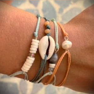 four handmade string bracelets on a wrist