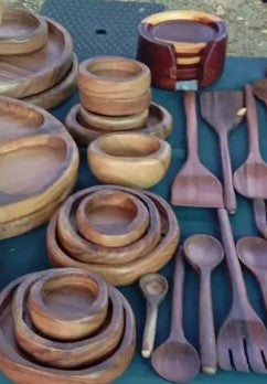 Collection of wooden kitchen utensils including bowls, spoons, and forks on a blue surface.